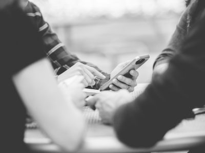 A closeup shot of people using their smartphone with a blurred background in black and white
